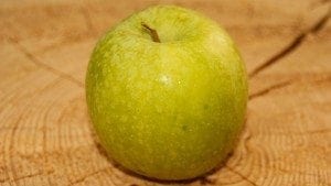 Ein frischer Apfel liegt auf einem Baumstamm